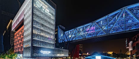 A modern building with illuminated signage and a prominent bridge structure.