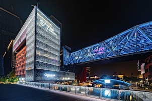 Un edificio moderno con señalización iluminada y una estructura de puente destacada.