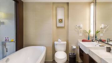 Un baño moderno con una bañera independiente, inodoro y tocador con espejo.