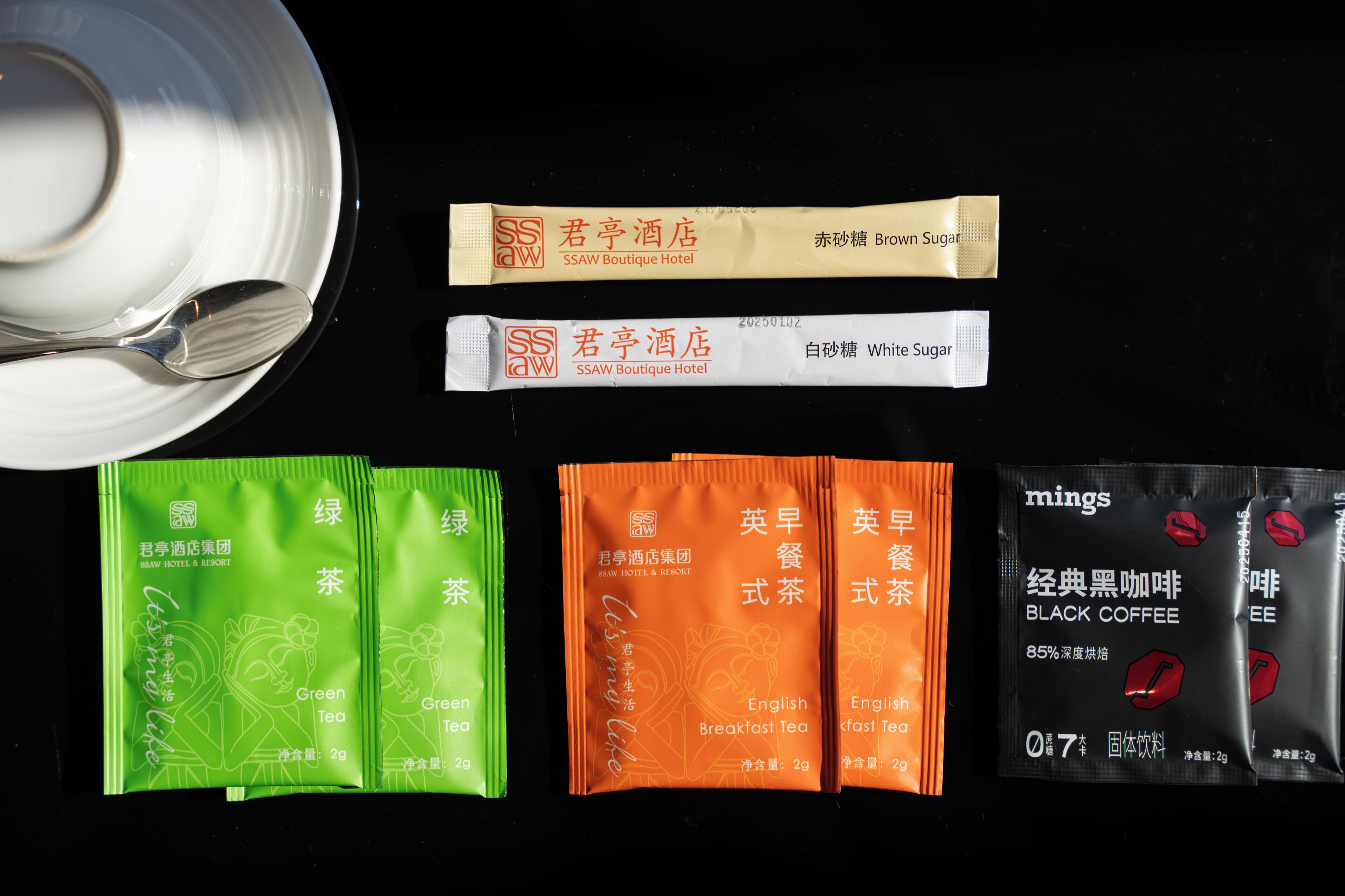 Various tea and coffee products, including green tea, English breakfast tea, and black coffee, arranged on a black surface.