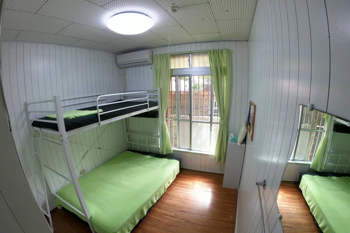 A room with bunk beds, a window with curtains, and an air conditioning unit.