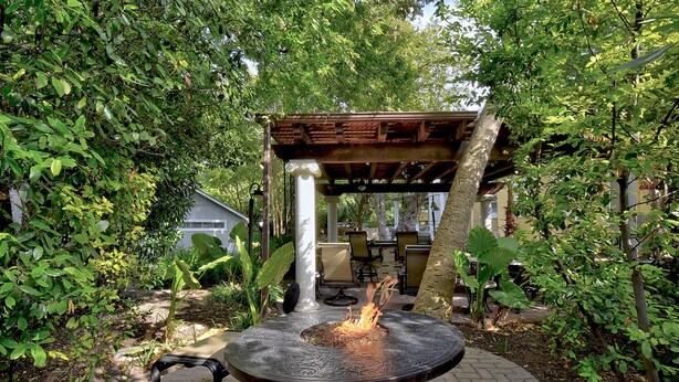 An outdoor patio with a round table, a fire pit, and a wooden pergola. - Adams Guest Full House, King Williams Area, Southtown (San Antonio)