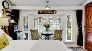 A bedroom with a bed, a table with chairs, a clock, a sign, and a window with a view of the outdoors. - Adams Guest Full House, King Williams Area, Southtown (San Antonio)
