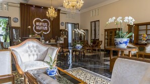 Un vestíbulo amplio con una suntuosa araña, muebles elegantes y un llamativo letrero 'KUTUS KUTUS'.