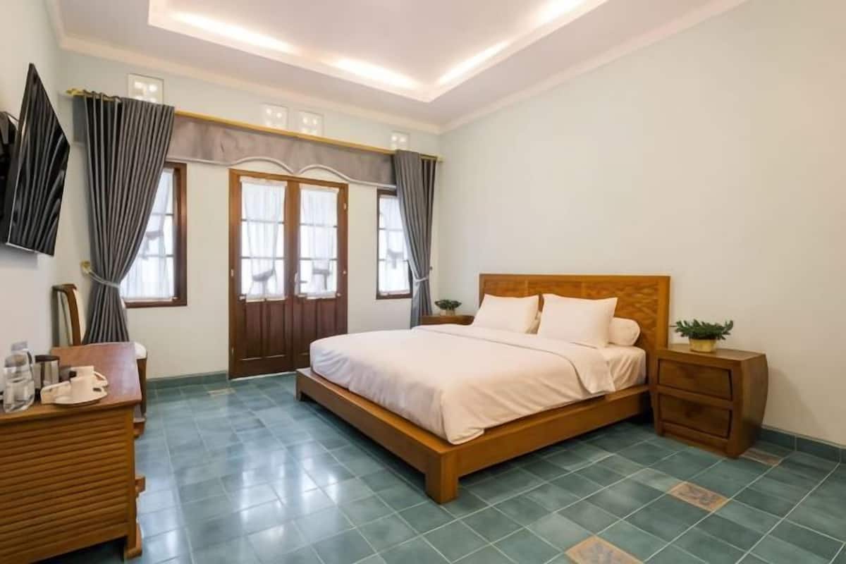 A bedroom with a bed, bedside tables, a dresser, and a window with curtains.