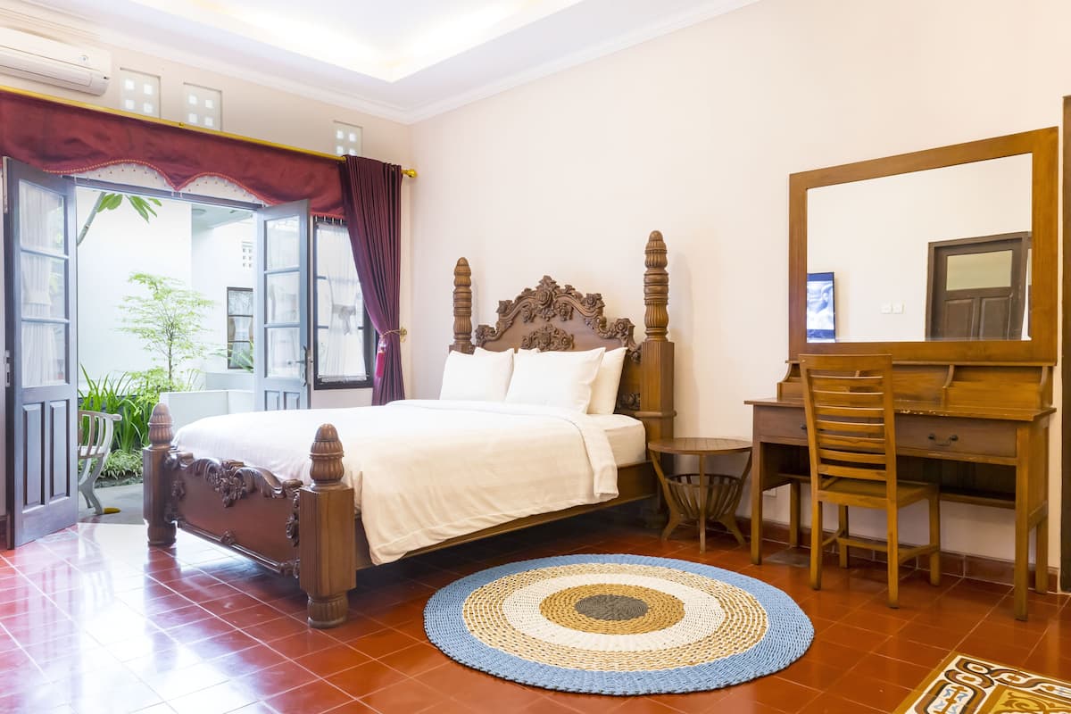 A bedroom with a wooden bed, a desk, and a chair.