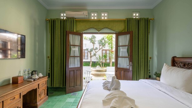 Habitación de hotel con cama, un escritorio de madera, televisión y vistas al exterior.
