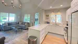 A spacious kitchen with white cabinets, a central island, and a large window.