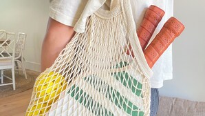 A person holding a macrame bag with bottles.