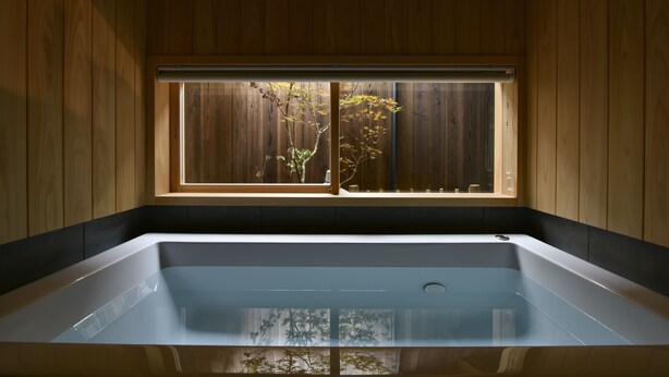 Une salle de bain moderne avec une grande baignoire, des murs en bois et une fenêtre donnant sur la forêt.