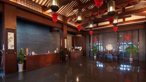 A spacious lobby with a polished floor, wooden reception desk, and traditional decor including lanterns and potted plants. - Xitang Yanyu Jiangnan Jinglan Hotel (Jiaxing)