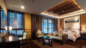 A hotel room with a wooden ceiling, a bed, a sofa, a desk, and a chair. - Xitang Yanyu Jiangnan Jinglan Hotel (Jiaxing)
