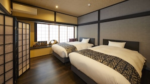 A hotel room with two beds, a traditional sliding door, a window with a view, and a ceiling with recessed lighting. - Rinn Tsukinuke (Kyoto)