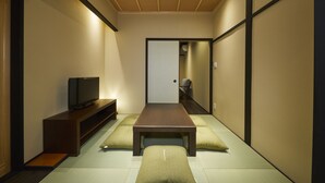 A traditional Japanese-style room with tatami flooring, a low wooden table, and a television on a stand. - Rinn Tsukinuke (Kyoto)