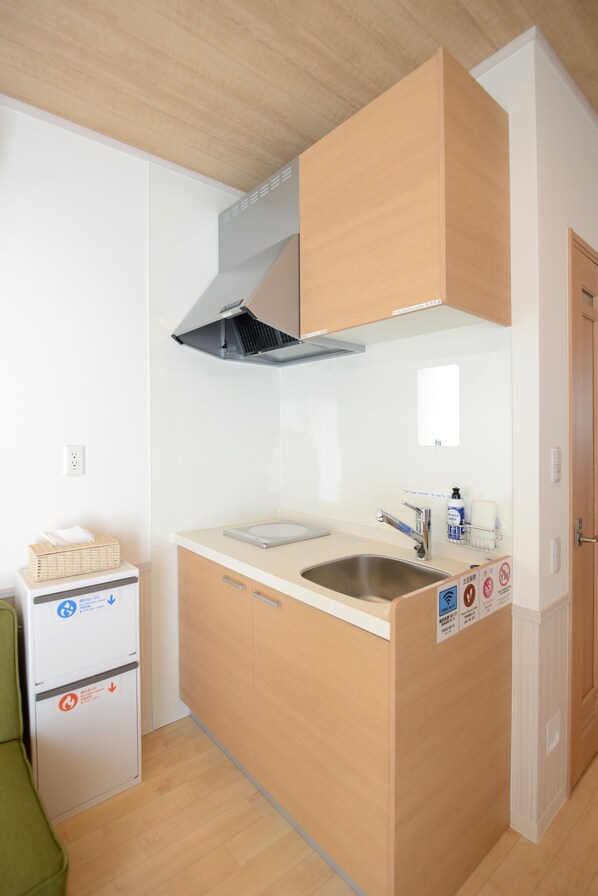 A compact kitchen with a sink, stove, and a small refrigerator. - Tourist Villa Kawaguchiko (Fujikawaguchiko)