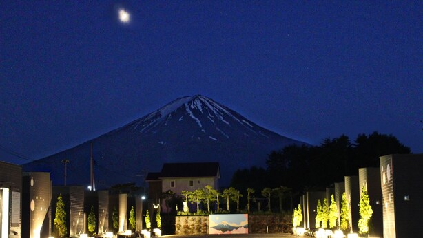 Une vue nocturne d’une montagne, avec un bâtiment au premier plan.