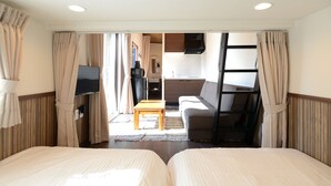 Une chambre d’hôtel avec deux lits, une télévision, une kitchenette et un canapé.