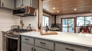 Une cuisine moderne dotée d’appareils électroménagers en acier inoxydable, d’un grand îlot central et d’une cheminée en pierre.