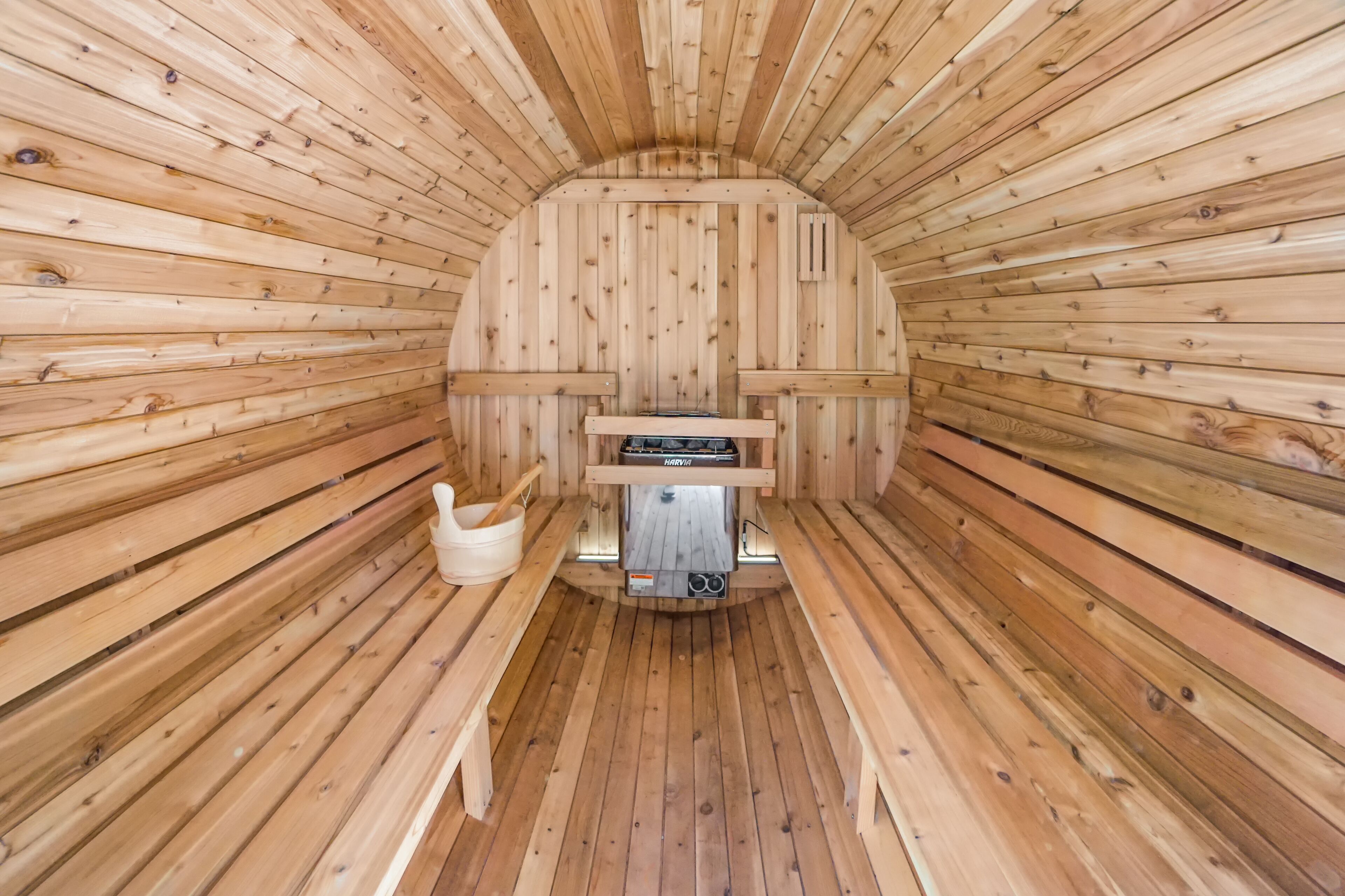 Eine Sauna mit Holzwänden und Bänken, einem Sitzheizkörper und einem Eimer.