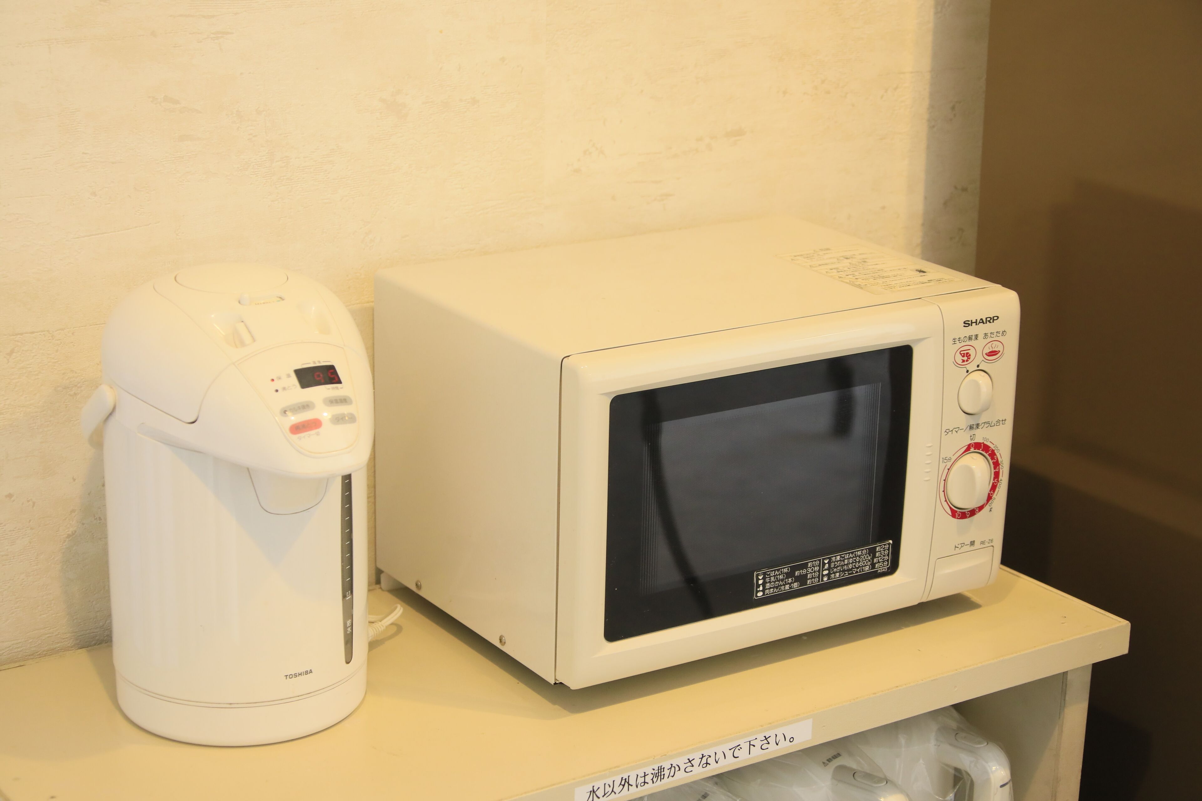 Un four à micro-ondes et un cuiseur à riz sont posés sur une étagère.