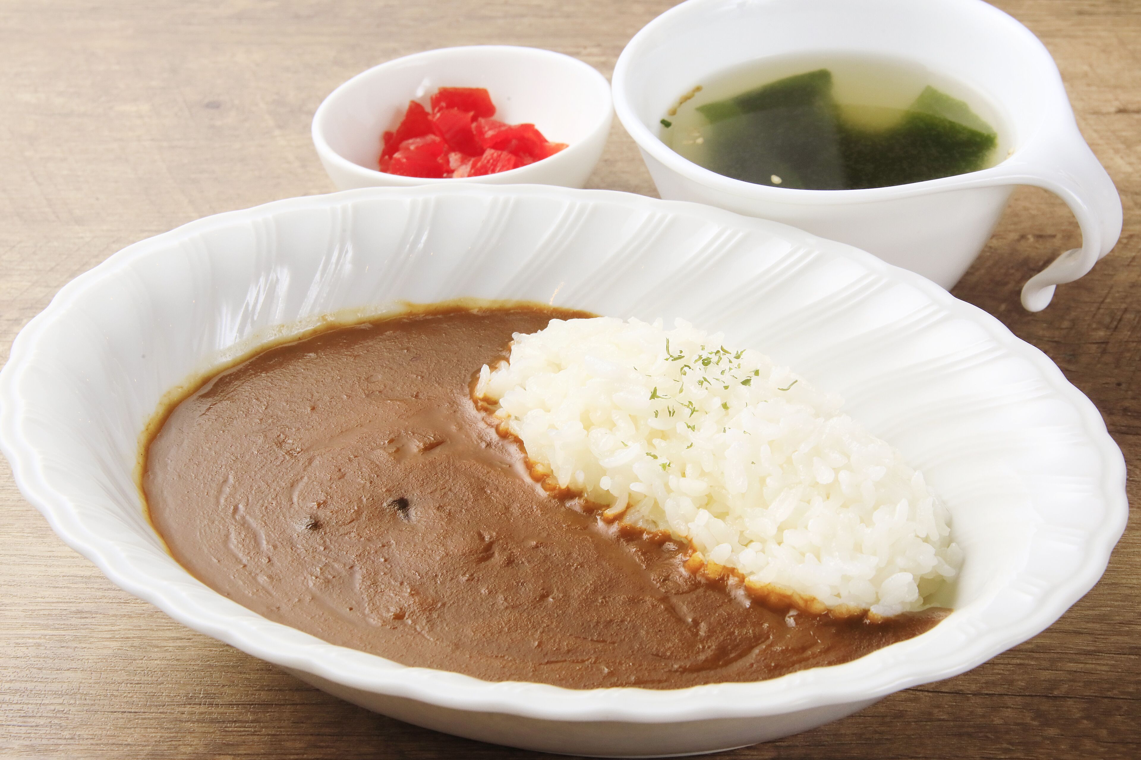 Un tazón de arroz con frijoles, acompañado de tomates picados y una taza de té.
