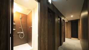 Et hotel med trævægge, et bruseområde og et tæppe på gulvet.
