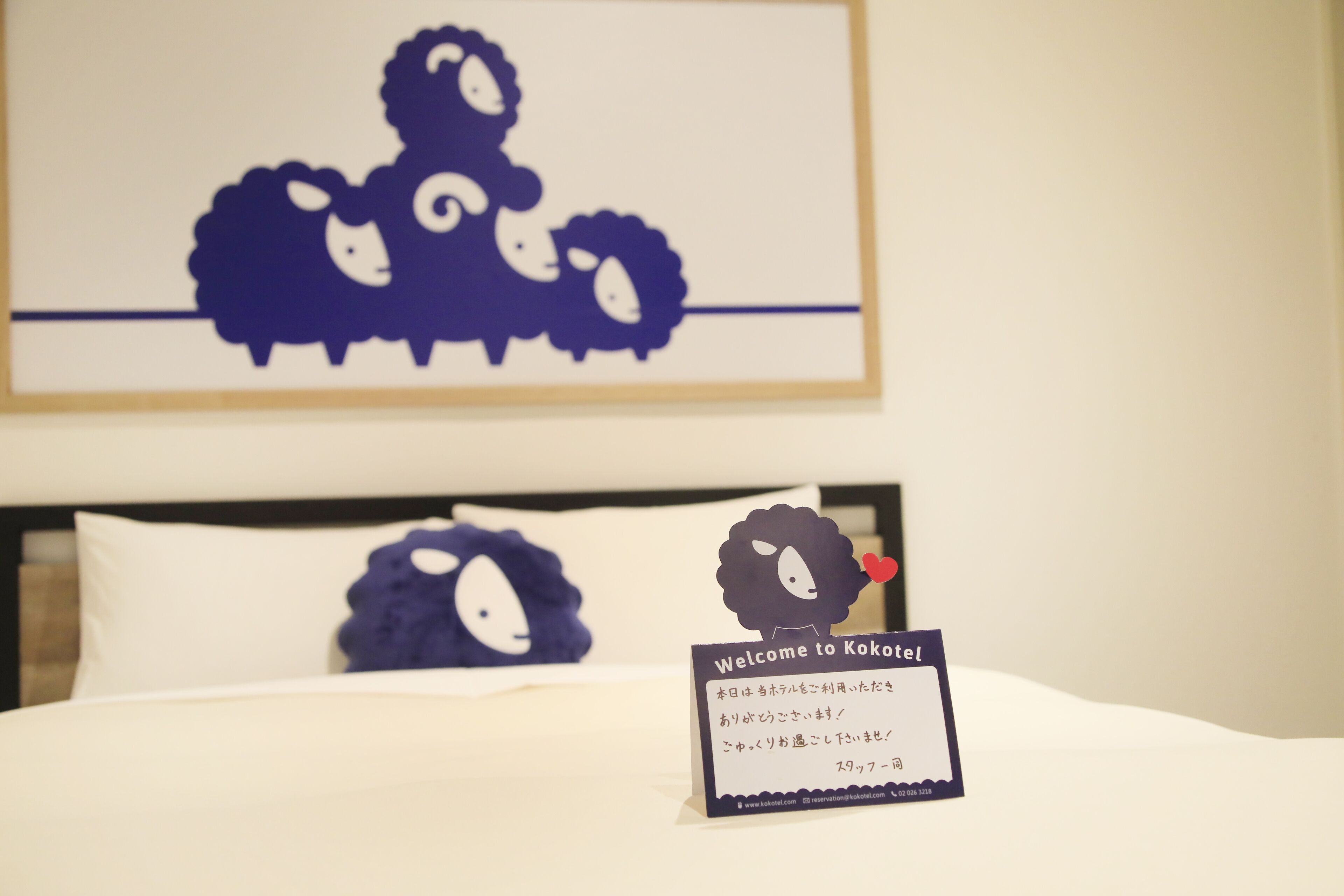 A bed with a welcome sign and a wall decoration of sheep.