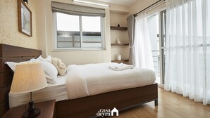 Een slaapkamer met een bed, bedlamp, raam en gordijnen.