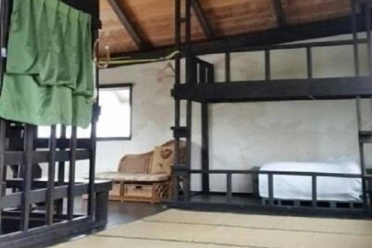 A room with a sloped ceiling, a ceiling fan, a bunk bed, and a window.