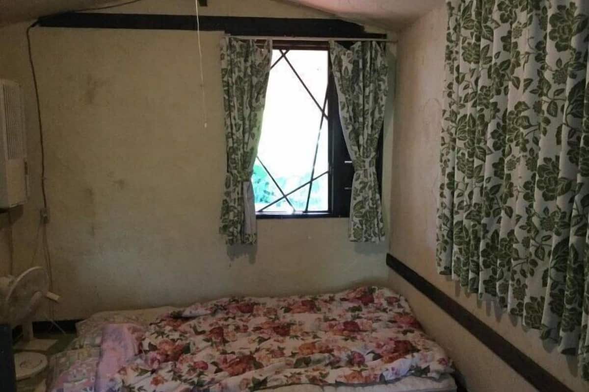 A small room with a single bed, a window with curtains, and a radiator.