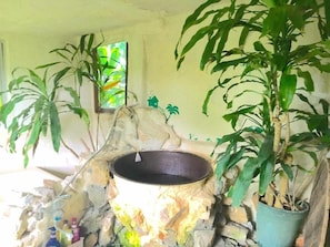 A rustic room with a stone wall, a hanging pot, and a window with a view of greenery. - Muwmin Farm - Hostel (Nakijin)