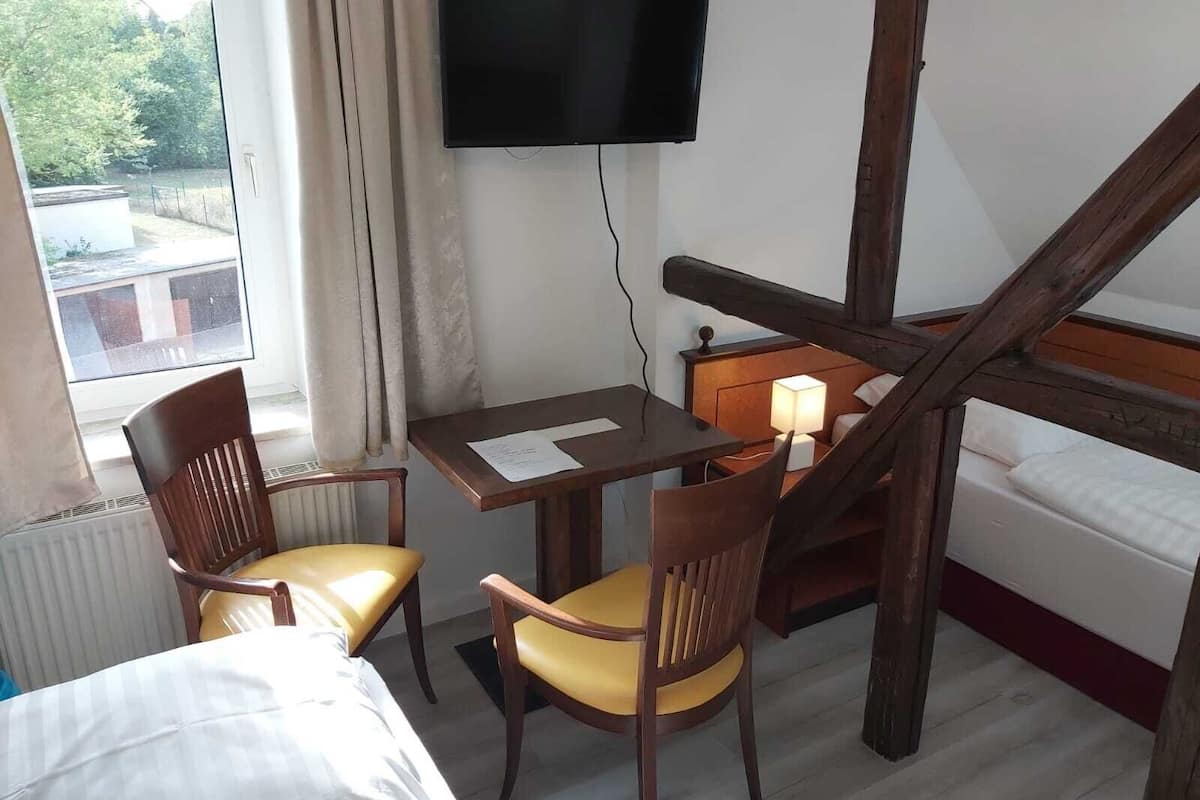 Ein Hotelzimmer mit einem Bett, einem Schreibtisch mit zwei Stühlen, einem Fernseher und einer Treppe.