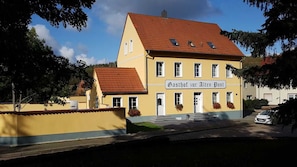 Un bâtiment à deux étages, avec une façade jaune et un toit rouge, portant l’inscription « Gasthof zur Alten Post ».