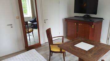Ein Zimmer mit einem Bett, einem Holztisch, einem Fernseher und einem Kleiderschrank.