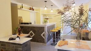 Een bar met krukken, een toonbank en planken met flessen en glazen.