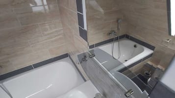 A modern bathroom with a bathtub, a sink, and a shower.