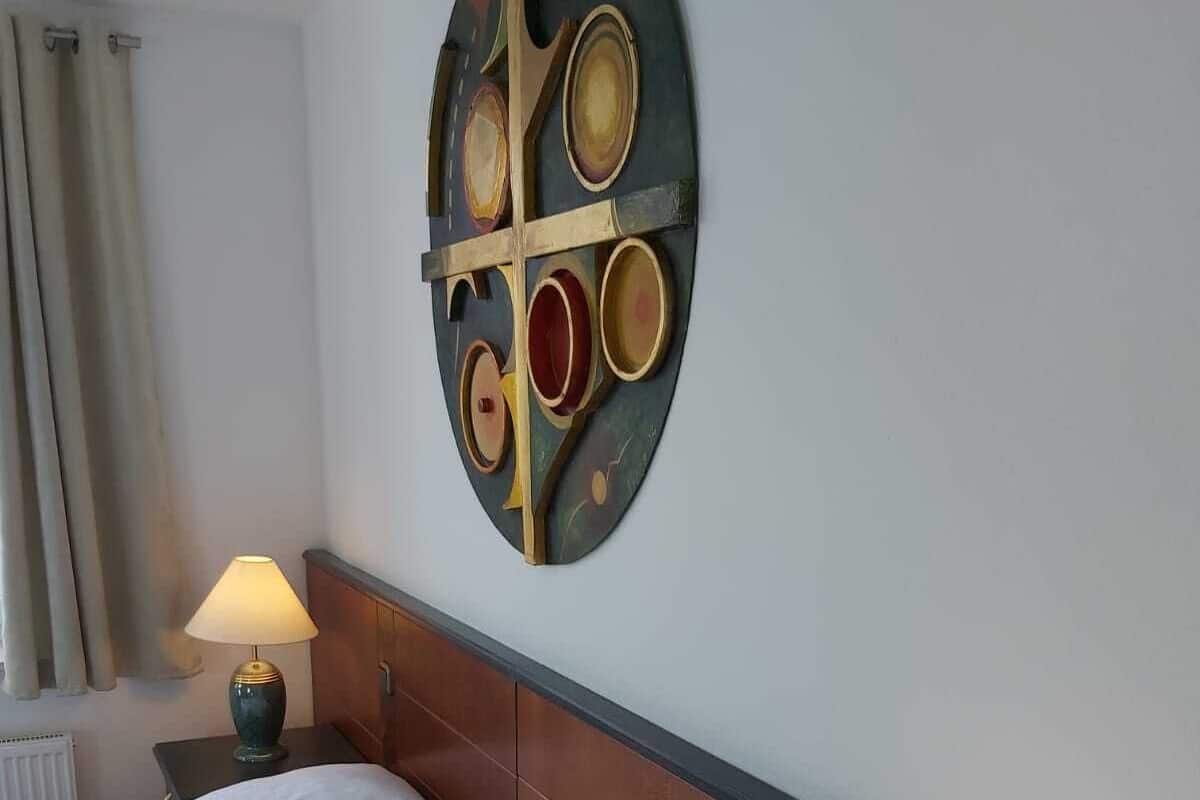 Ein Hotelzimmer mit einem Bett, zwei Nachttischlampen, einer Wanddekoration und einem Fenster mit Vorhängen.