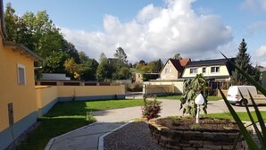 Een woonwijk met een verharde oprit, een pad van stenen en een plantenborder met grind en beplanting.
