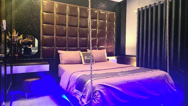 A modern bedroom with a tufted headboard, a hanging chair, and a large mirror. - Kha Thy Hotel (Ho Chi Minh City)