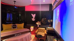 A hotel room with a bed, a chair, a small table, a mirror, and a TV screen displaying a person. - Kha Thy Hotel (Ho Chi Minh City)