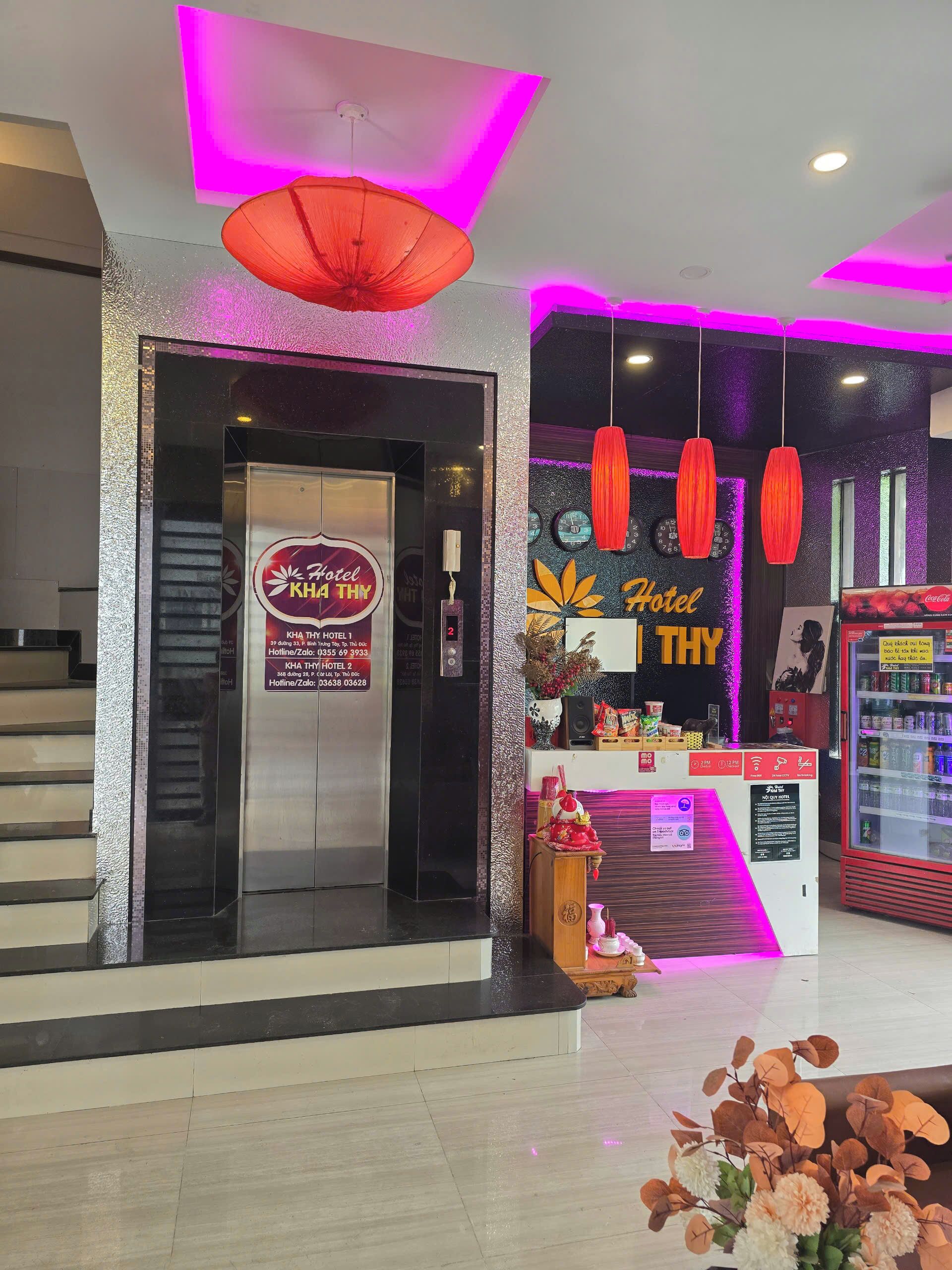 A hotel entrance with a sign, a Coca-Cola refrigerator, and a staircase.