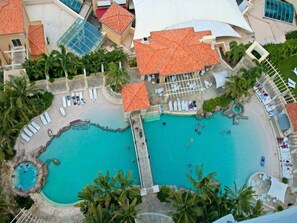 An aerial view of a resort with two large swimming pools, a beach area, and a covered pavilion. - Ocean & Riverview at Chevron Renaissance (Surfers Paradise)