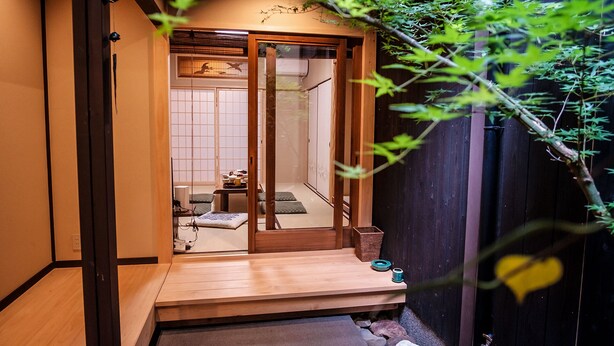 A traditional Japanese-style room with tatami flooring, a sliding door, and a small garden area with a bamboo plant. - Kyomachiya KINKA (Kyoto)