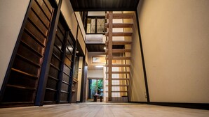 A corridor with wooden paneling, a staircase, and a view into a room with a table and chairs. - Kyomachiya KINKA (Kyoto)