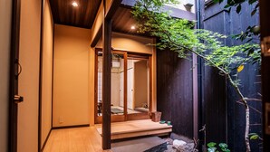 A traditional Japanese-style entrance with a wooden floor leading to a room with sliding doors. - Kyomachiya KINKA (Kyoto)