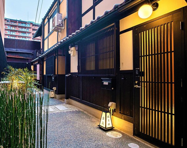 A traditional Japanese building with a black gate and a small lantern.