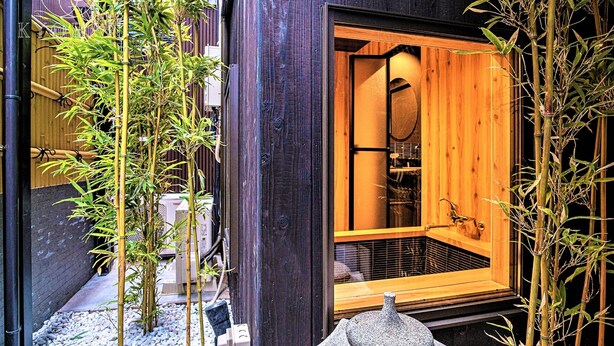 A traditional Japanese-style room with a wooden sliding door, a stone basin, and bamboo plants. - Kyorana Kyogetsutei (Kyoto)