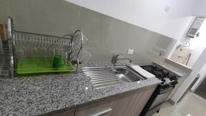 Une cuisine moderne dotée d’un plan de travail en granit, d’un évier en acier inoxydable et d’une cuisinière intégrée.