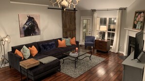 A living room with a dark sofa, a coffee table, a blue armchair, a wooden cabinet, and a fireplace.