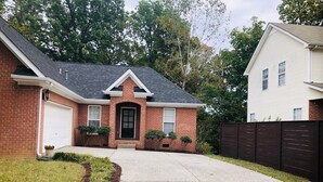 A two-story house with a brick facade, a black front door, and a driveway leading to a garage.